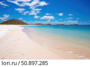 Pristine white sand beach meeting turquoise ocean under a cloudy blue sky. Стоковое AI-изображение, AI-художник Иван Рябоконь / Фотобанк Лори