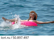Woman Water Floating. Woman splashes water with feet, relaxing on pink ring in clear blue ocean on a sunny day. Стоковое фото, фотограф svetograph / Фотобанк Лори