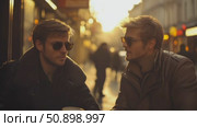 Confident men in leather jackets and shades engage in a deep discussion amidst the golden glow of a city evening. Стоковое AI-видео, аниматор Данила Большаков / Фотобанк Лори