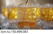 Refreshing golden beverage streams into a chilled glass filled with sparkling ice and effervescent bubbles on a glistening wet surface. Стоковое AI-видео, аниматор Данила Большаков / Фотобанк Лори