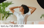 A serene woman with rich curly hair stretching arms upward in a peaceful indoor setting, embracing a moment of tranquil comfort. Стоковое AI-видео, аниматор Данила Большаков / Фотобанк Лори