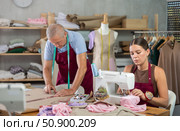 Girl master sew clothes in sewing machine, senior craftsman draw dress pattern. Стоковое фото, фотограф Яков Филимонов / Фотобанк Лори