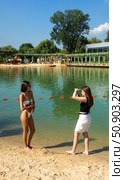 Красивые девушки фотографируются в купальниках на фоне воды./ Pioneer Pond. Beach recreation on the water near the pond in Gorky Park, Moscow, 2025. Beautiful girls are photographed in bathing suits against the backdrop of water. Редакционное фото, фотограф Iva Noel / Фотобанк Лори