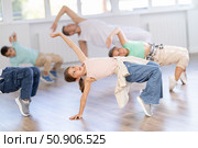 Happy sporty ten years old girl training movements of vigorous dance on floor during group class in dance school. Стоковое фото, фотограф Яков Филимонов / Фотобанк Лори