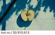 Still life concept: Half apple on a weathered surface with contrasting light and shadow patterns. Стоковое AI-изображение, AI-художник Данила Большаков / Фотобанк Лори