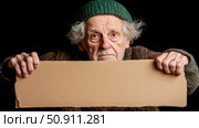 Poverty concept: Senior man holding a blank cardboard sign with a desperate look for campaign purpose, design for print, card, poster. Стоковое AI-изображение, AI-художник Данила Большаков / Фотобанк Лори