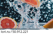 Citrus slices splashing dramatically into water, generating dynamic liquid crown against dark blurred background, highlighting fresh juice and hydration concept. Стоковое AI-видео, аниматор Данил Руденко / Фотобанк Лори