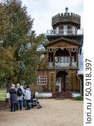 Architectural Appreciation: A group of sightseers admires a detailed, multi-story wooden building with a tower, showcasing its unique facade and ornate woodwork, Музей-усадьба Ильи Ефимовича Репина "Здравнёво", Беларусь. Редакционное фото, фотограф Данила Большаков / Фотобанк Лори