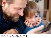 Father and son little boy laughing and using phone. They watching funny videos together, playing games on smartphone. Concept technology, smart phone addicted. Fun weekend activity. Modern fatherhood. Стоковое фото, фотограф Марина Демидюк / Фотобанк Лори