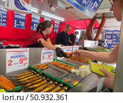 Городская ярмарка в центре города. Палатка с рыбой и морепродуктами. Продавец протягивает покупателю банковский терминал, покупательница оплачивает покупку картой. Вагенинген. Нидерланды. Редакционное фото, фотограф Мария Фетисова / Фотобанк Лори