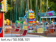 A group of swings is suspended from a chain, with one blue-red in the middle. Russia. Moscow. 25.07.25. Редакционное фото, фотограф Ярославский Максим / Фотобанк Лори