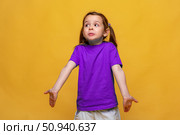 Puzzled and clueless little girl with arms out, shrugging her shoulders, on yellow background, saying: who cares, so what, I don't know. Negative human emotions, facial expressions, life attitude. Стоковое фото, фотограф Ирина Михайличенко / Фотобанк Лори
