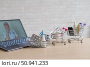Online medicine and pharmacy concept. A female doctor conducts an online consultation and recommends medications. Mini trolley with tablets at the laptop. Стоковое фото, фотограф Михаил Решетников / Фотобанк Лори