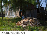 Женщина переносит привезённые к дому дрова. Редакционное фото, фотограф Дмитрий Киселёв / Фотобанк Лори