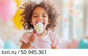 A joyful birthday celebration: A young girl indulges in a sweet treat, her face smeared with cream, creating a moment of pure delight and happiness. Стоковое AI-изображение, AI-художник Данила Большаков / Фотобанк Лори