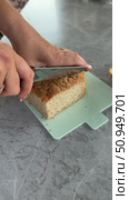 A woman is slicing bread. Close-up of hands holding a knife and the bread. Vertical video. Стоковое видео, видеограф Vadzim Yakubovich / Фотобанк Лори