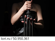 BDSM concept. A woman in a leather corset holds a black lash with a long fringe. Role-playing games for adults. Close-up of sex toys for domination. The whip in female hands. Стоковое фото, фотограф Михаил Решетников / Фотобанк Лори