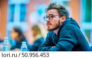 Engaged Young Man with Beard and Glasses Attending a Lecture or Conference, Displaying Deep Concentration and Thoughtful Participation. Стоковое AI-изображение, AI-художник Данила Большаков / Фотобанк Лори