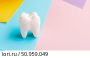 A clean white tooth model resting on a vibrant multi-colored geometric surface, promoting oral hygiene and healthy dental care awareness. Стоковое AI-изображение, AI-художник Данила Большаков / Фотобанк Лори