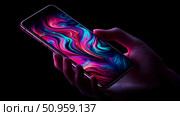 A human hand gripping a sleek mobile device showcasing a brilliant, flowing digital artwork on its screen, suitable for tech advertisement or digital media promotion. Стоковое AI-изображение, AI-художник Данила Большаков / Фотобанк Лори