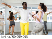 Beautiful young woman at dance salon with her african american partner dancing active boogie-woogie dance. Стоковое фото, фотограф Яков Филимонов / Фотобанк Лори