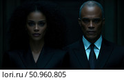 A compelling depiction of two composed individuals in dark suits, exuding an aura of serious intent and professional gravitas in a dimly lit scene. Стоковое AI-изображение, AI-художник Данила Большаков / Фотобанк Лори