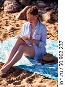 Woman Immersed in a Captivating Book While Relaxing on a Sunny Beach. Стоковое фото, фотограф Aleksandr Golubev / Фотобанк Лори