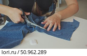 With a piece of scissors, the tailor cuts out a palm-shaped outline from denim. Стоковое видео, видеограф Strunov David / Фотобанк Лори