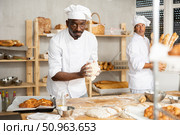 Professional African baker kneading dough on floured table. Стоковое фото, фотограф Яков Филимонов / Фотобанк Лори