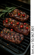 Juicy seared beef steaks sizzling on a charcoal grill with fresh rosemary and vibrant cherry tomatoes, ideal for a gourmet cookbook or a backyard barbecue event promotion. Стоковое AI-изображение, AI-художник Данила Большаков / Фотобанк Лори