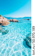 Stunning Tropical Seascape Featuring Luminous Aquamarine Water with Light Caustics, Coastal Boulders, and a Distant Mountain Range Horizon. Стоковое AI-изображение, AI-художник Данила Большаков / Фотобанк Лори