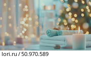 Cozy wellness retreat display showcasing rolled turquoise and white towels, bath products, and a lit candle with warm blurred luminescence. Стоковое AI-видео, аниматор Данила Большаков / Фотобанк Лори