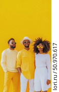 A vibrant group portrait of three individuals in stylish apparel against a striking yellow wall. Стоковое AI-видео, аниматор Данила Большаков / Фотобанк Лори