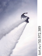 An athlete flies into the sky on a flightboard view from below. Two powerful jet streams from the flightboard carry the plane up into the sky. Experience the thrill of flyboarding high above the water. Стоковое фото, фотограф Владимир Разгуляев / Фотобанк Лори