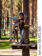 Adventurous Girls Navigate the Rope Park Among Towering Trees on a Sunny Day. Редакционное фото, фотограф Aleksandr Golubev / Фотобанк Лори