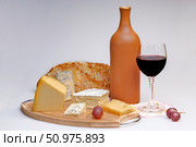 Сырная тарелка, бутылка и бокал с красным вином, хлеб и ягоды винограда. Стоковое фото, фотограф Евгений Дробжев / Фотобанк Лори