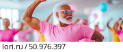 Senior Man Flexing Bicep in Pink Shirt at Fitness Class. Стоковое AI-изображение, AI-художник Данила Большаков / Фотобанк Лори