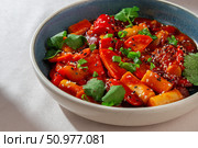 Korean rice cakes cooked in spicy gochujang sauce with vegetables, sesame seeds and fresh herbs served in ceramic bowl under natural daylight. Стоковое фото, фотограф Aleksandr Gavrilychev / Фотобанк Лори