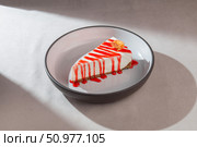 Soft cheesecake with graham crust and strawberry syrup topped with an edible flower on ceramic plate under soft natural light. Стоковое фото, фотограф Aleksandr Gavrilychev / Фотобанк Лори