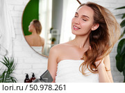 Woman dries her hair with a towel while enjoying the morning light in a bright bathroom setting. Стоковое фото, фотограф Сергей Толмачёв / Фотобанк Лори