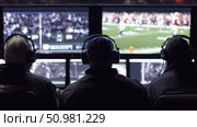 Sports broadcast team monitors live football game footage on multiple screens, coordinating production, replays, and coverage from a dark control room environment. Стоковое AI-изображение, AI-художник Катерина Бондарец / Фотобанк Лори