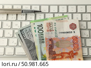 На белой клавиатуре лежат купюры сто долларов, сто евро и пять тысяч рублей вместе с ручкой. Стоковое фото, фотограф Дмитрий Серегин / Фотобанк Лори