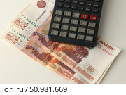 Две купюры по пять тысяч рублей и калькулятор. Стоковое фото, фотограф Дмитрий Серегин / Фотобанк Лори