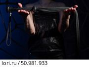 Black leather lash in the hands of an unrecognizable woman. Cropped photo of bdsms toys. Punishment and pleasure. A woman stands in the dark and holds a whip in her palms. Стоковое фото, фотограф Михаил Решетников / Фотобанк Лори