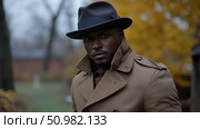 Stylish Man in Autumnal Setting: Portrait of a Dapper Gentleman in a Trench Coat and Fedora Hat. Стоковое AI-изображение, AI-художник Данила Большаков / Фотобанк Лори