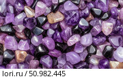 Close-up of tumbled amethyst and black stones: a vibrant collection of purple and black gems. Стоковое AI-изображение, AI-художник Данила Большаков / Фотобанк Лори