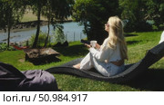 A woman enjoys a serene day in nature, relaxing with her phone. Стоковое видео, видеограф Cantemir Dumitru / Фотобанк Лори