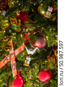 A decorated tree featuring a maneki-neko, gold cat, red and gold balls, paper crane, and festive lights. Редакционное фото, фотограф Софья Соломонова / Фотобанк Лори