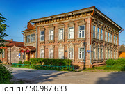 Старинный деревянный особняк с мелкой резьбой на наличниках окон и во фасаду летним солнечным вечером. Редакционное фото, фотограф Владимир Шипикин / Фотобанк Лори