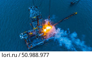 An offshore drilling rig operates in deep sea mining. Flames and smoke emerge from the rig. Стоковое AI-изображение, AI-художник Евгения Пархоменко / Фотобанк Лори